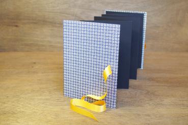 Leporello standing, black zig-zag pages, yellow ribbon